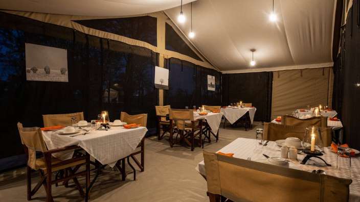 Tische und Stühle in einem Zelt mit Bildern von Elefanten an der Wand