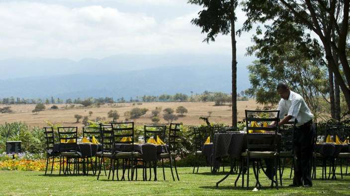 Ein Mann bereitet Tische und Stühle auf einer Wiese vor