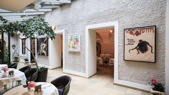 Ein Esszimmer mit Tischen und Stühlen und einem Gemälde an der Wand