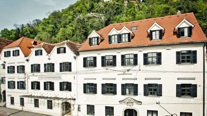 Ein großes weißes Gebäude mit schwarzen Fensterläden heißt schlossberghotel