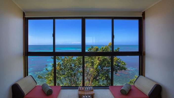 Ein Wohnzimmer mit einem großen Fenster mit Blick auf das Meer