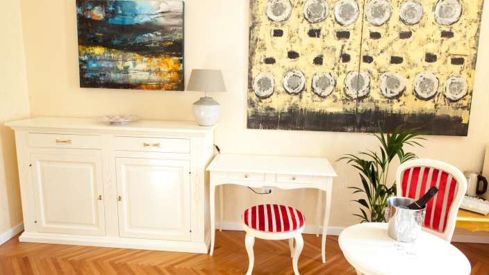 Ein Wohnzimmer mit einem Tisch und einem Stuhl und einem Gemälde an der Wand