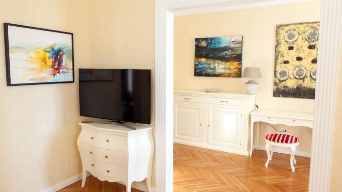 Ein Wohnzimmer mit einem Fernseher und zwei Gemälden an der Wand