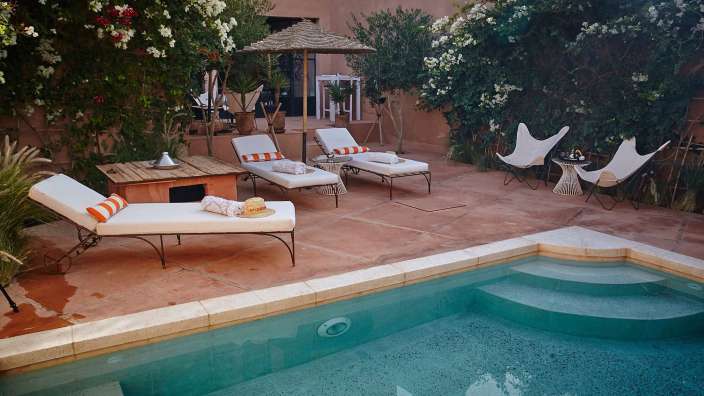 Ein Swimmingpool mit Liegestühlen und Sonnenschirmen umgeben