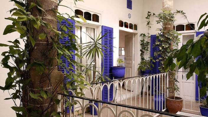 Ein Balkon mit blauen Fensterläden und vielen Pflanzen