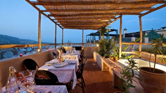 Tische und Stühle auf einer Terrasse mit einem Dach aus Stroh