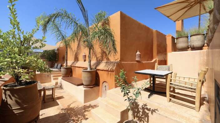 Eine Terrasse mit einem Tisch und Stühlen und einer Palme