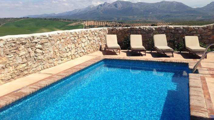 Ein Swimmingpool mit Liegestühlen und einer Steinmauer im Hintergrund