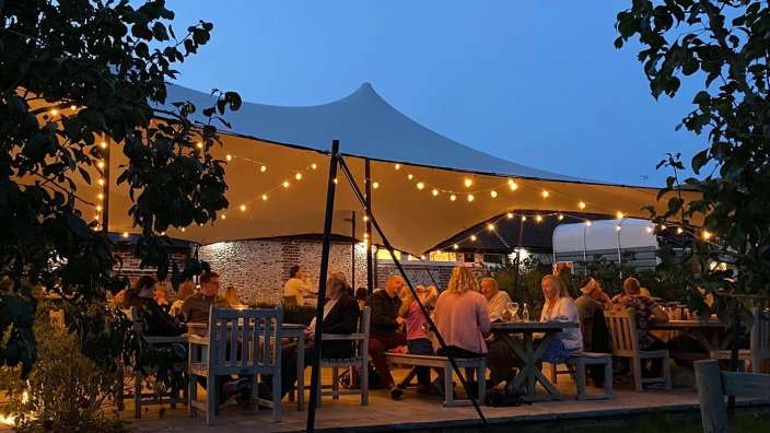 Eine Gruppe von Menschen sitzt an einem Tisch unter einem Zelt