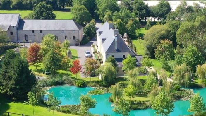 Ein großes Haus mit einem Teich im Vordergrund