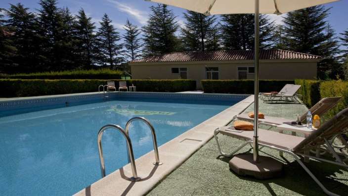 Ein Swimmingpool mit einem Sonnenschirm und Liegestühlen davor