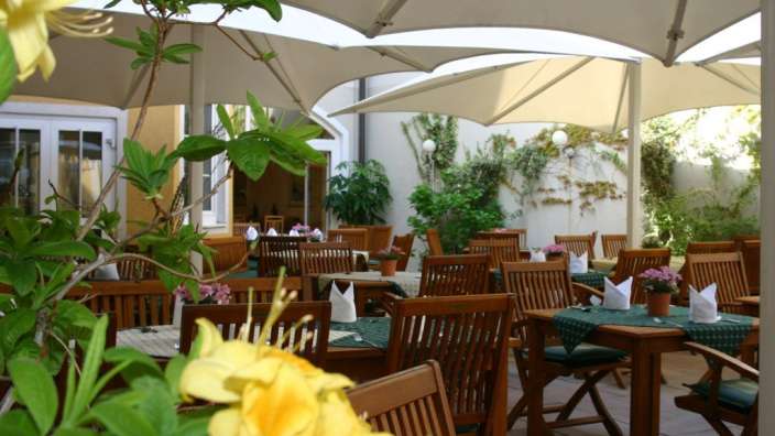 Eine Terrasse mit Tisch und Stühlen und Regenschirmen