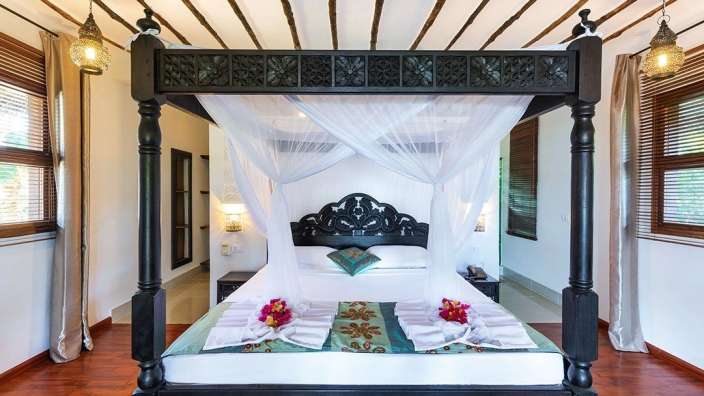 Ein Schlafzimmer mit einem Himmelbett und vielen Fenstern