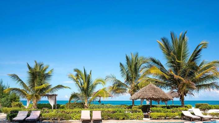 Ein großer Swimmingpool umgeben von Palmen und Liegestühlen