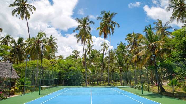 Ein Tennisplatz inmitten von Palmen an einem sonnigen Tag