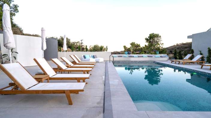 Ein Swimmingpool mit Liegestühlen und Sonnenschirmen umgeben