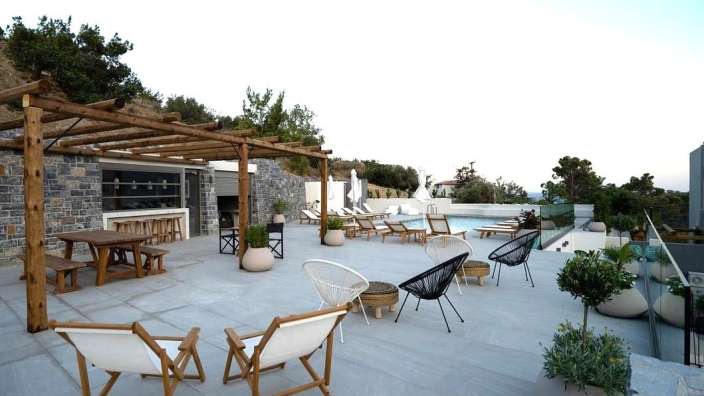 Eine Terrasse mit Stühlen und einem Tisch unter einer Pergola