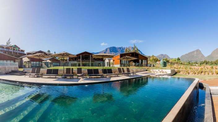 Ein großer Swimmingpool mit Liegestühlen und Sonnenschirmen umgeben