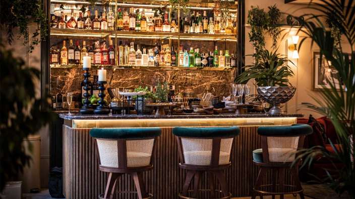 Eine Bar mit Stühlen und Flaschen an der Wand