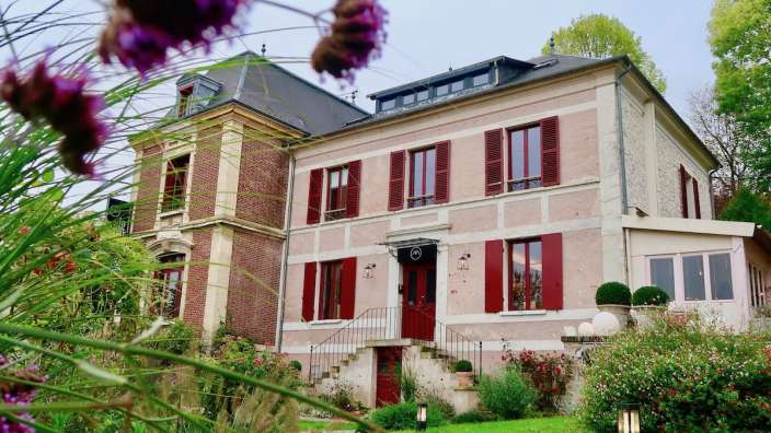 Ein großes rosa Haus mit roten Fensterläden