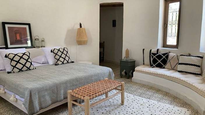Ein Schlafzimmer mit einem Bett und einer Bank mit schwarz-weißen Kissen
