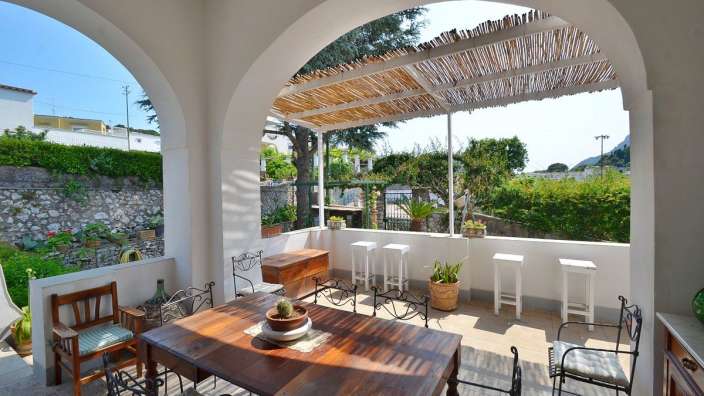 Ein Tisch und Stühle auf einer Terrasse mit einem Strohdach