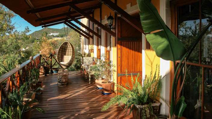 Ein hölzerner Balkon mit Pflanzen und einem Schaukelstuhl