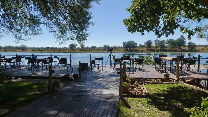 Ein Holzdeck mit Stühlen und Tischen an einem Fluss