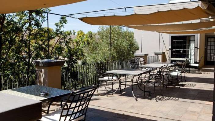 Tische und Stühle auf einem Balkon mit Sonnenschirmen