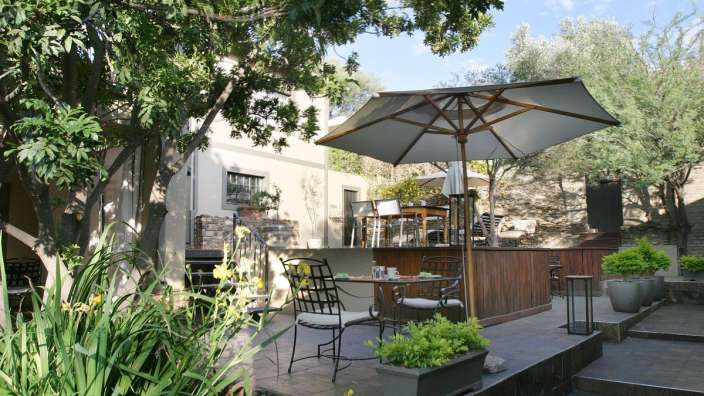 Eine Terrasse mit Tisch und Stühlen und einem Regenschirm