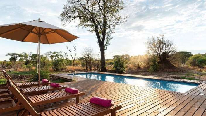 Liegestühle auf einem Holzdeck neben einem Swimmingpool