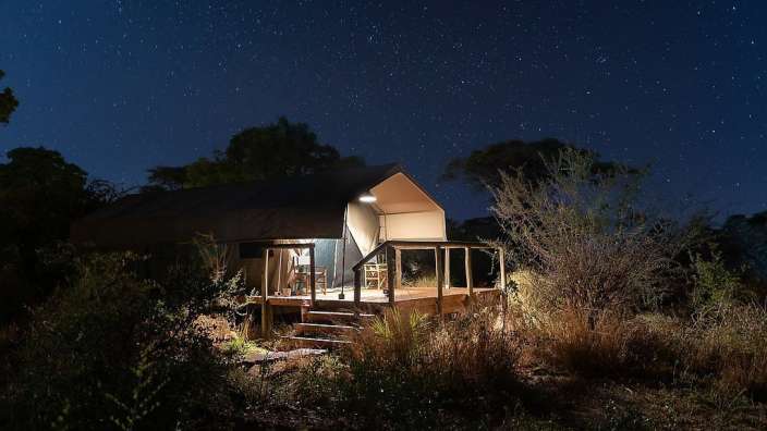 Ein Zelt mit einem Tisch und Stühlen auf der Veranda bei Nacht