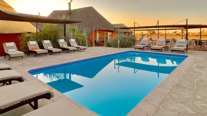 Liegestühle stehen um einen großen Swimmingpool