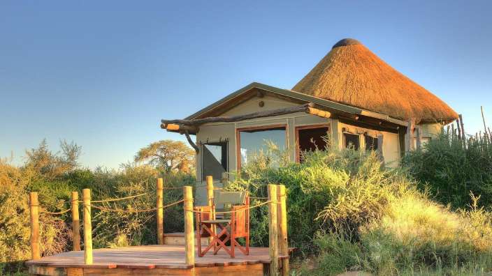 Ein kleines Haus mit Strohdach und einem Holzdeck