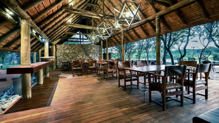 Ein Esszimmer mit Tisch und Stühlen unter einem Strohdach