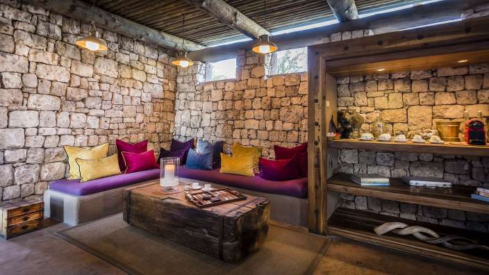 Ein Wohnzimmer mit lila und gelben Kissen und einem Holztisch