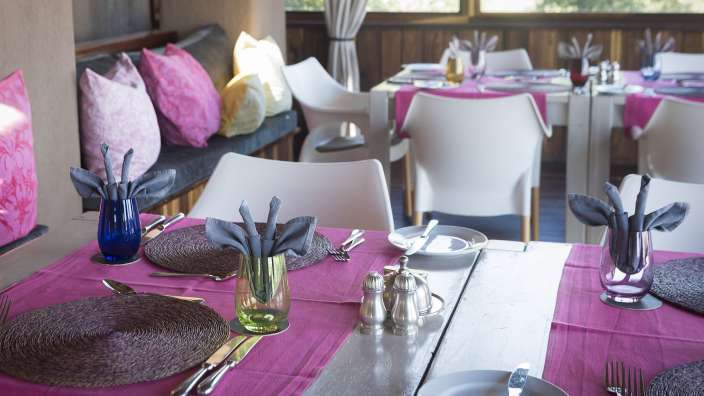Ein Tisch mit einem rosa Tischläufer und weißen Stühlen