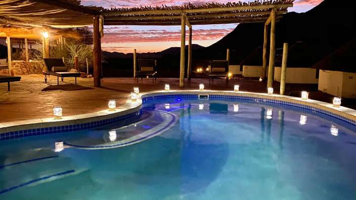 Ein Swimmingpool mit Kerzen und einem Sonnenuntergang im Hintergrund
