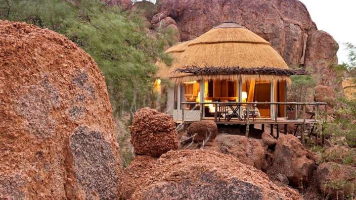 Eine kleine Hütte mit Strohdach sitzt zwischen zwei großen Felsen