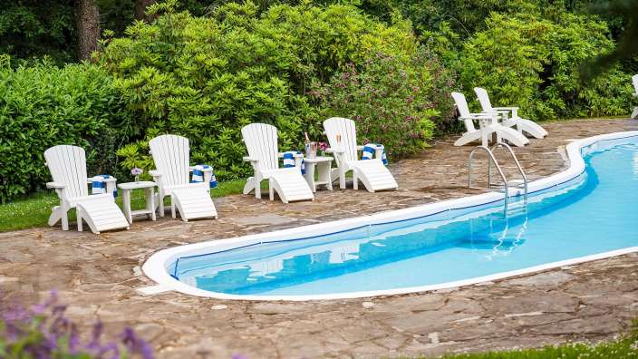 Eine Reihe von weißen Liegestühlen neben einem Swimmingpool