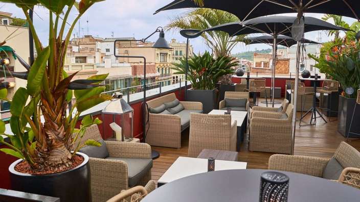 Eine Terrasse mit Tischen und Stühlen und schwarzen Regenschirmen