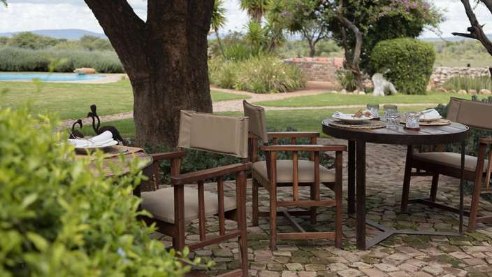Ein Tisch und Stühle auf einer Terrasse mit einem Pool im Hintergrund