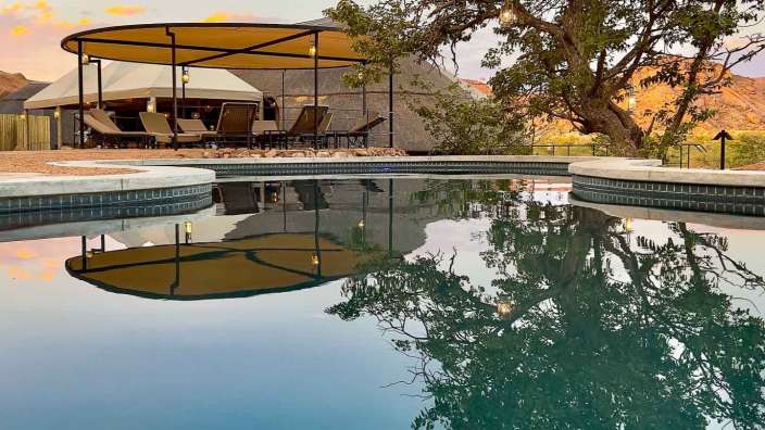 Ein Swimmingpool mit einem Zelt und Stühlen im Hintergrund