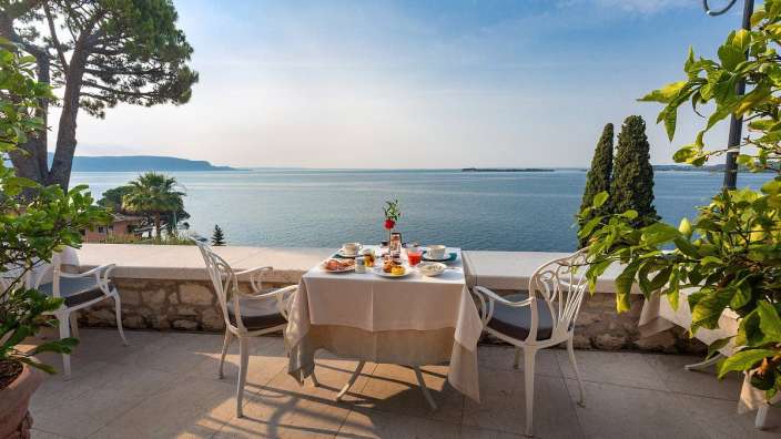 Ein Tisch und Stühle auf einer Terrasse mit Blick auf das Meer