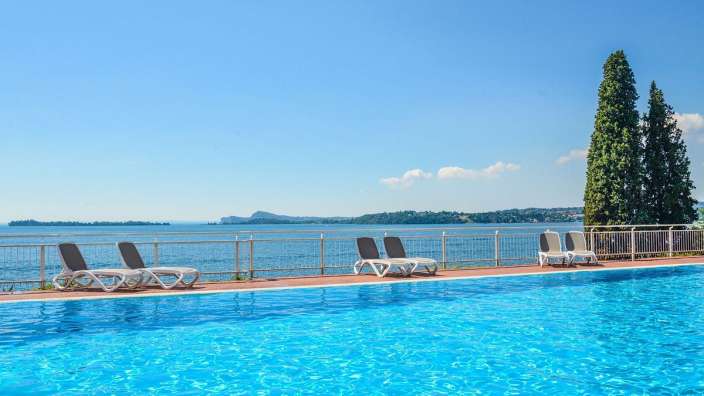 Liegestühle stehen neben einem Schwimmbad mit Blick auf den Ozean