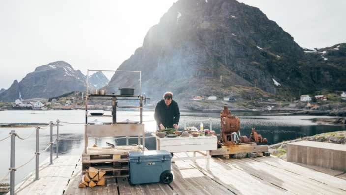 Ein Mann steht vor einem Tisch mit einem blauen yeti-Kühlschrank darauf