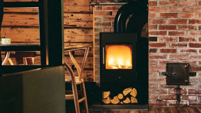 Ein Holzofen steht in einem Raum neben einem Backsteinmauer