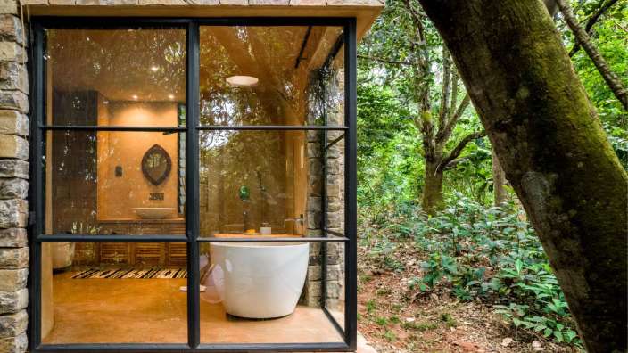 Ein Badezimmer mit einer Badewanne und einem Fenster mit Blick auf den Wald