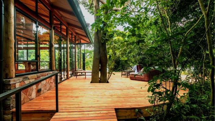 Ein Holzdeck führt zu einem Haus mit vielen Fenstern