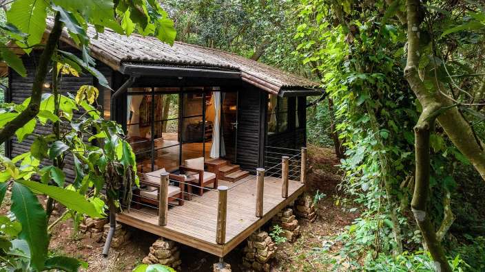 Ein kleines Holzhaus mit einer Holzterrasse im Wald